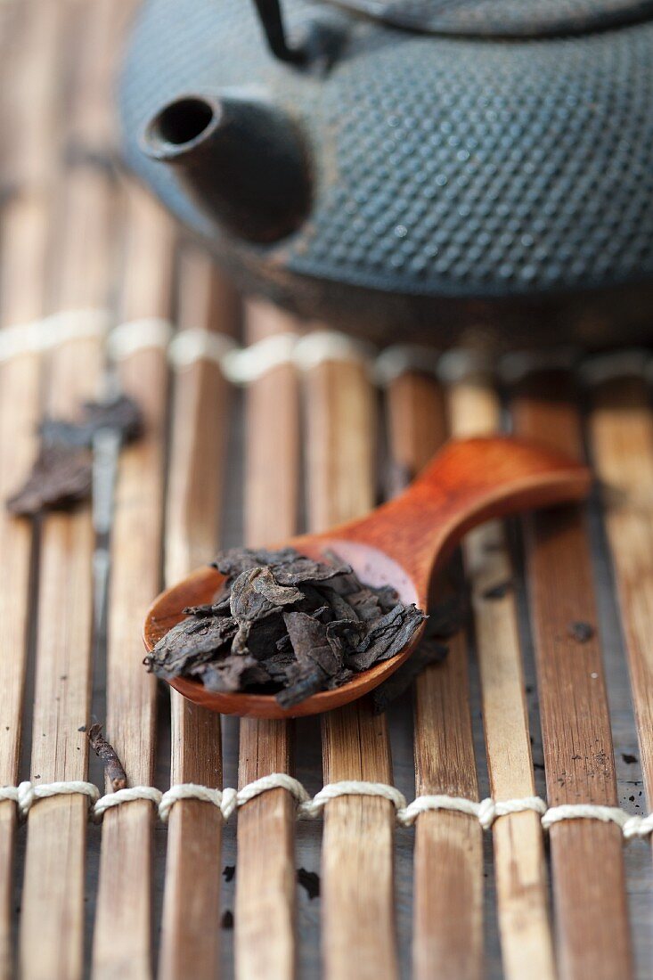 Stillleben mit Teekanne & Pu-Ehr-Teeblättern auf Löffel
