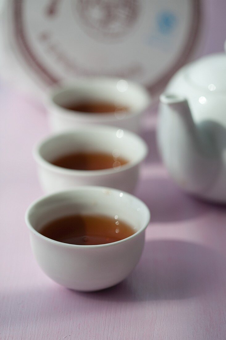 Aufgebrühter Pu-Ehr-Tee in weissen Teeschälchen