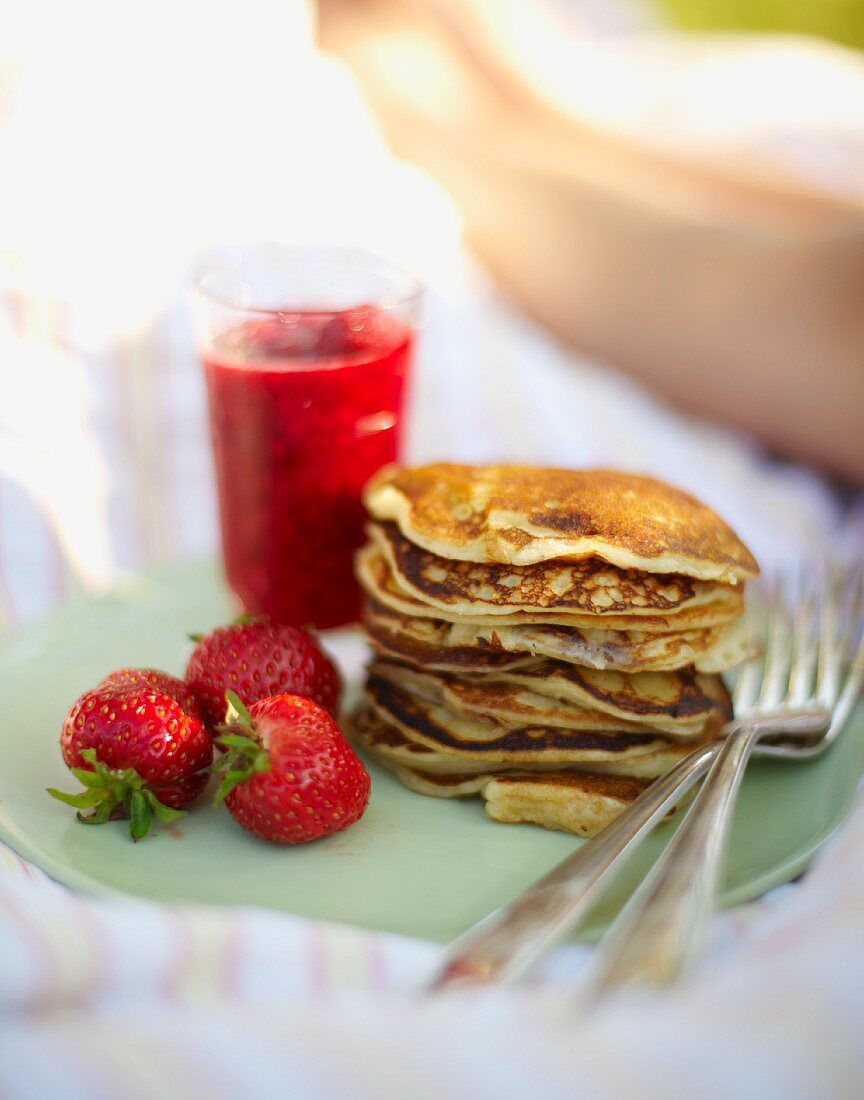 Pancakes mit Erdbeeren zum Frühstück im Bett auf der Wiese