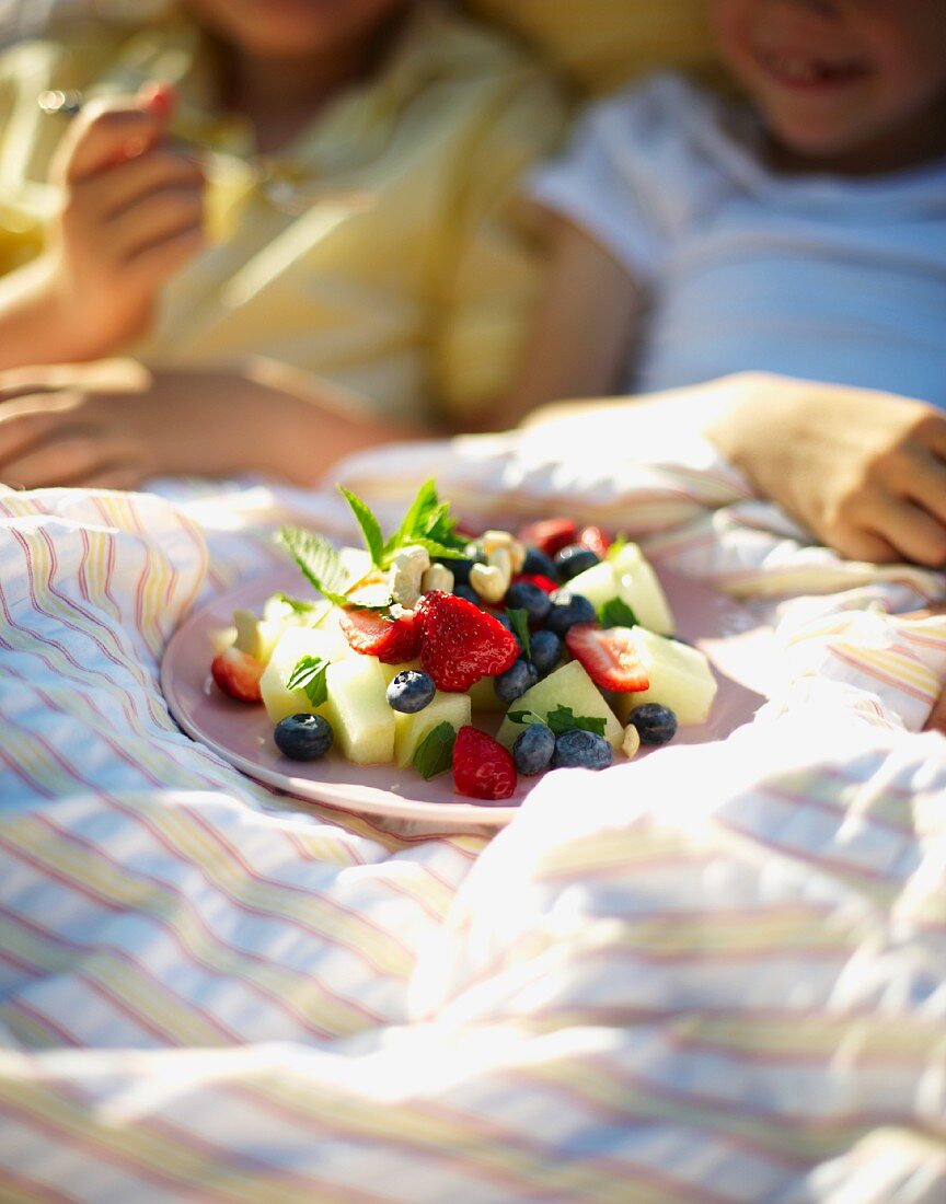 Fruit salad for breakfast in bed in a field