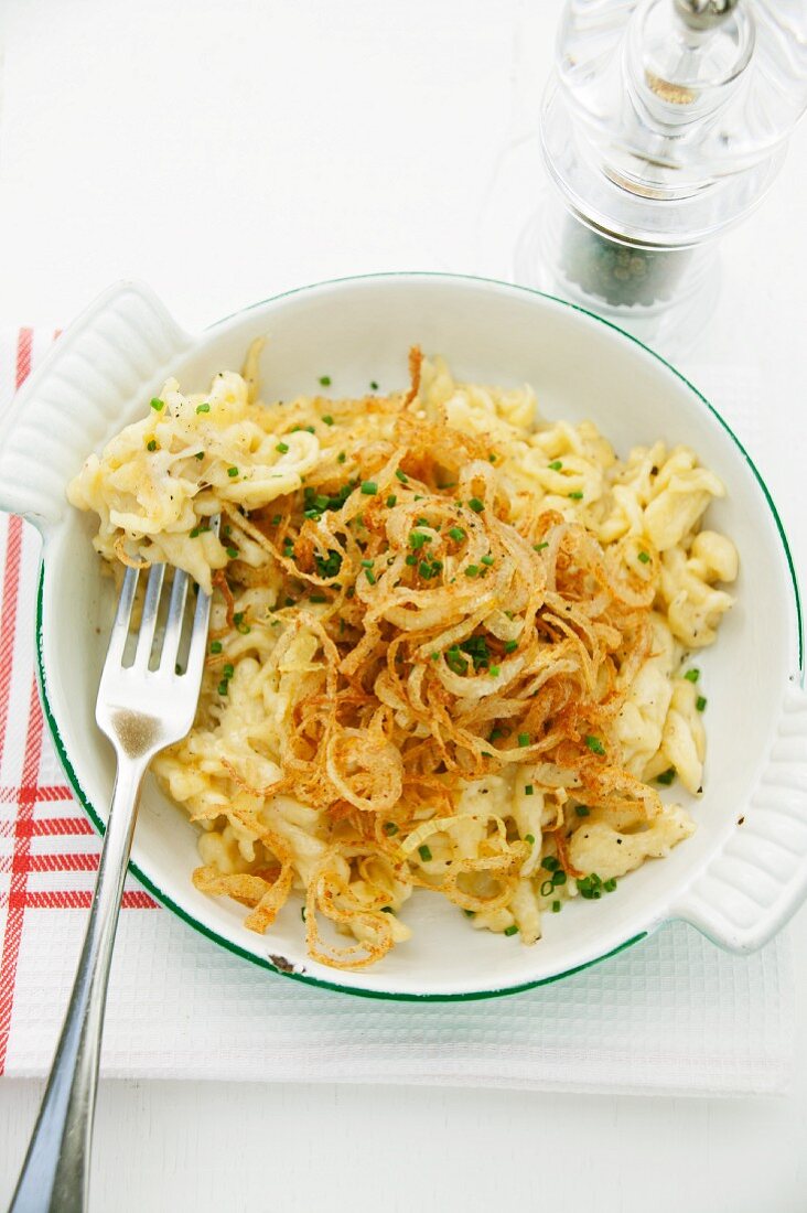 Cheese Spätzle (soft egg noodles from Swabia) with fried onions in an enamel baking dish
