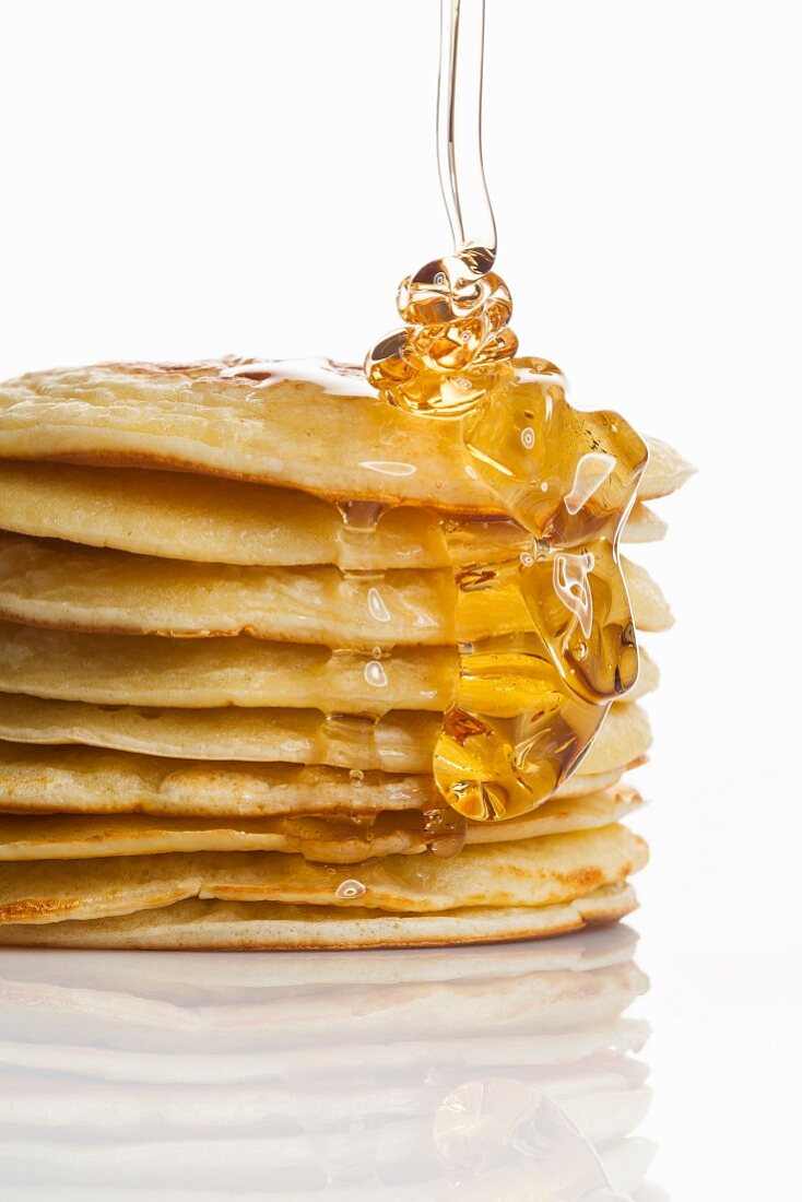 Honey being drizzled onto a stack of pancakes