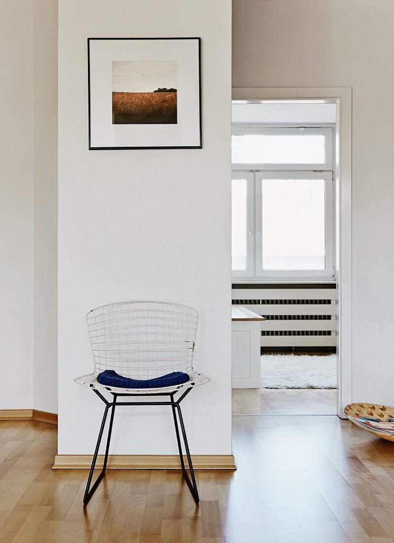 Classic mesh chair against wall with view into adjoining room through open door