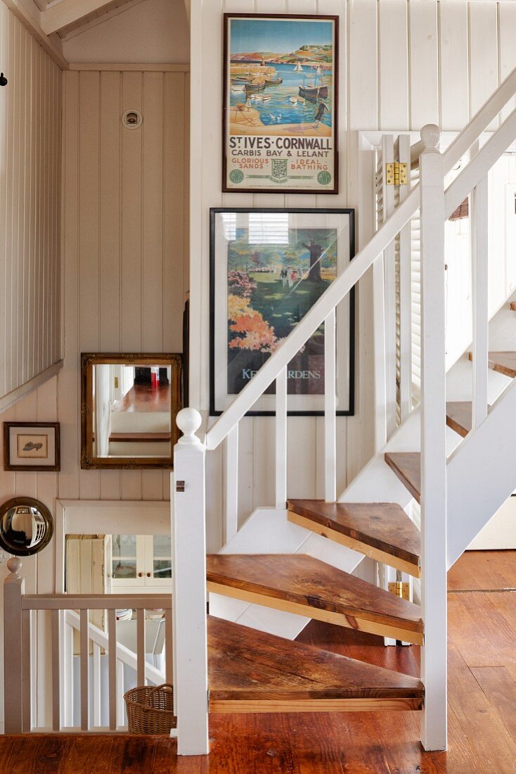 Wooden staircase with white balustrade in open-plan stairwell of beach house