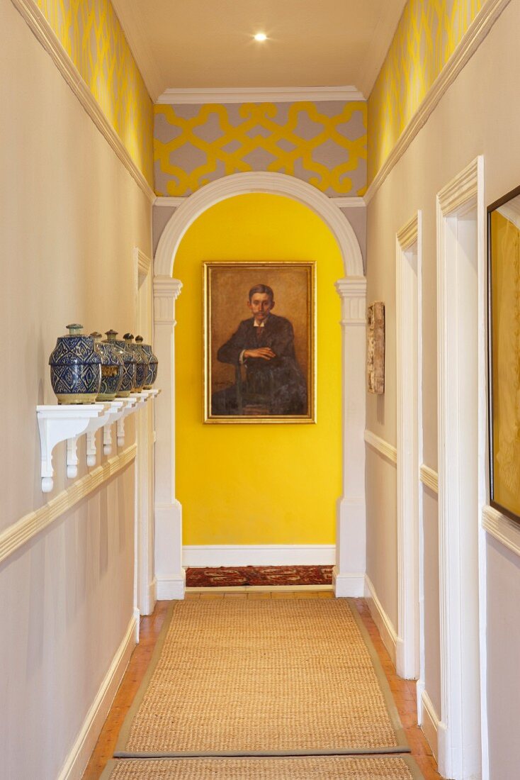 Moroccan ceramic pots on white bracket shelves in narrow hallway and wooden arch