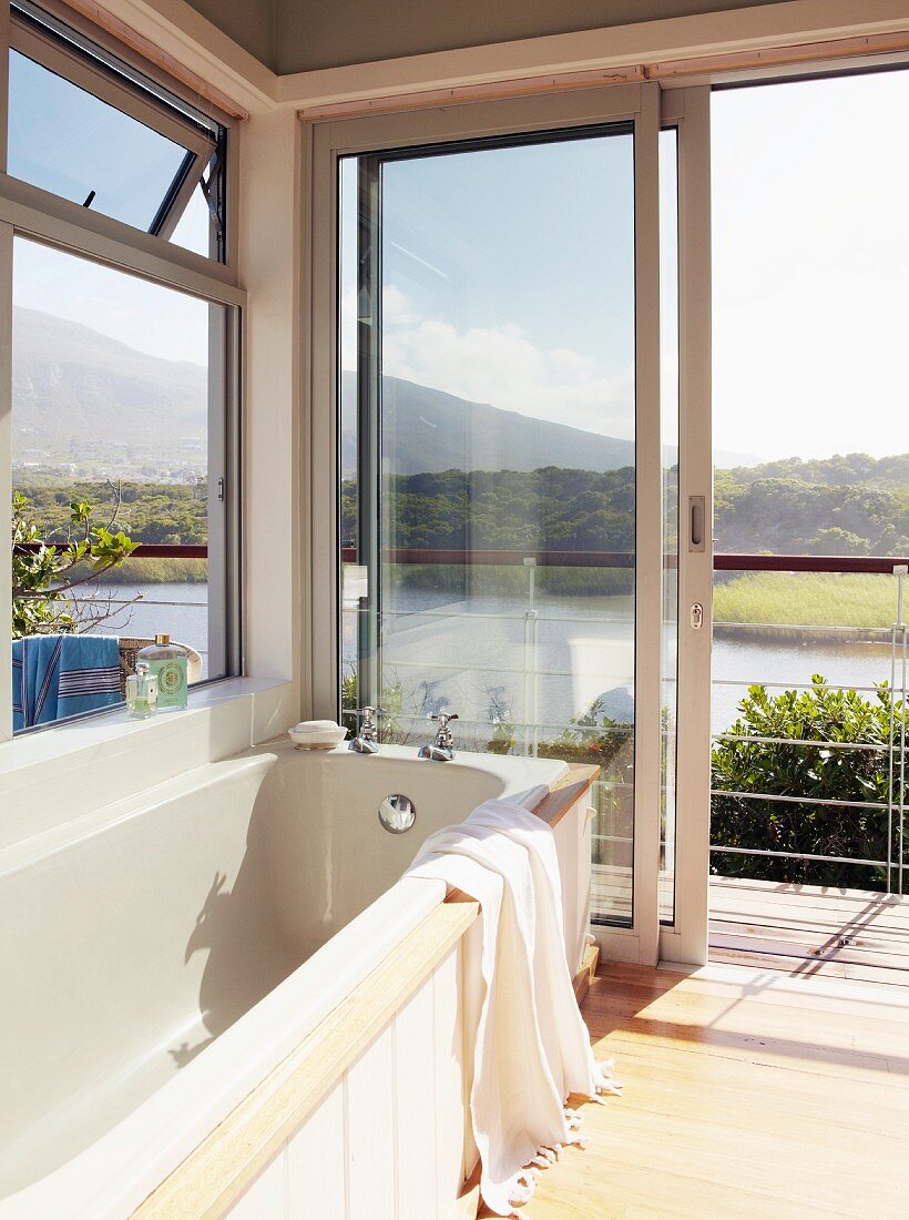 Badewanne mit herrlichem Blick durch geöffnete Terrassentür auf südafrikanische Lagunenlandschaft