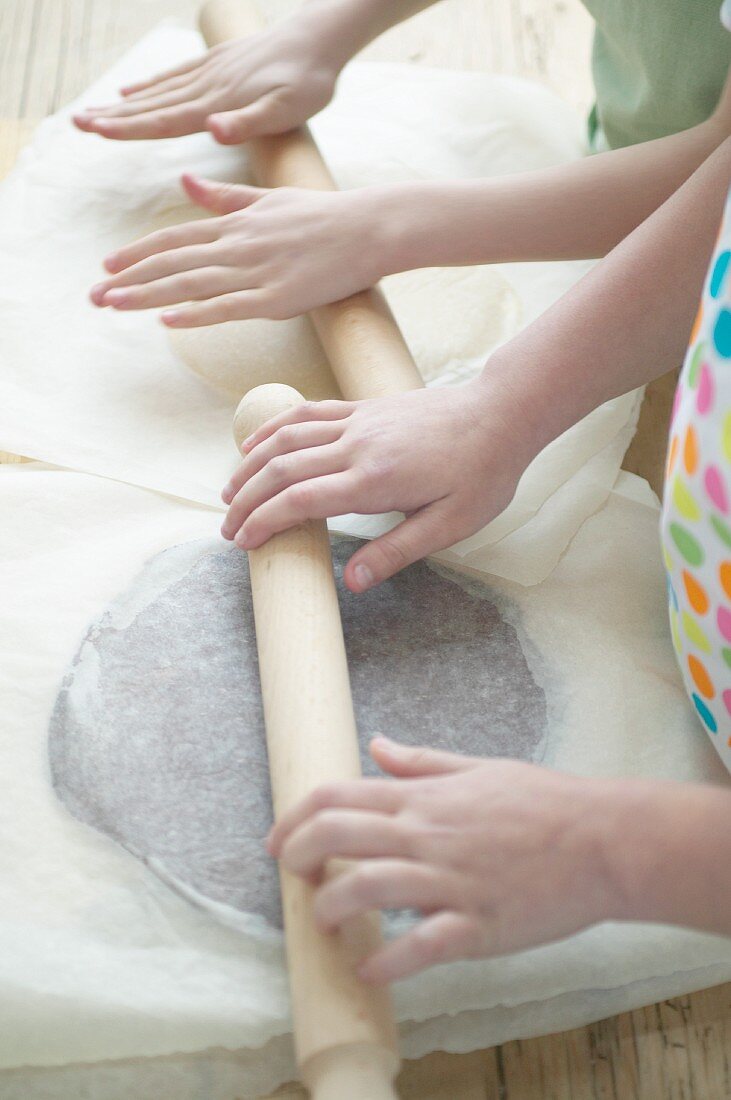 Kinderhände rollen Plätzchenteig aus