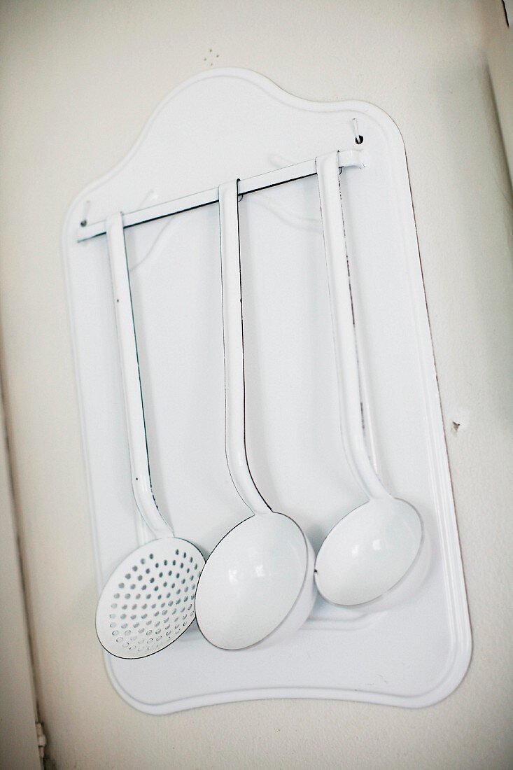 Various vintage ladles hung on white, metal rack