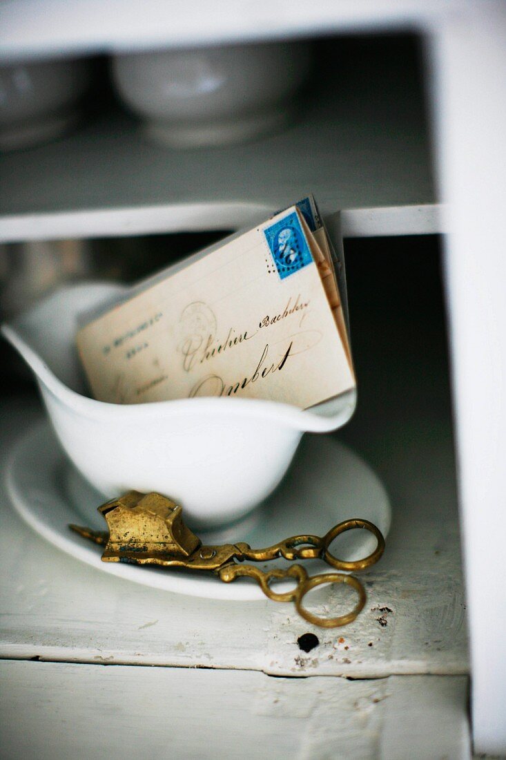 Vintage Messing Docht-Schere neben Briefen in Sauciere aus weißem Porzellan