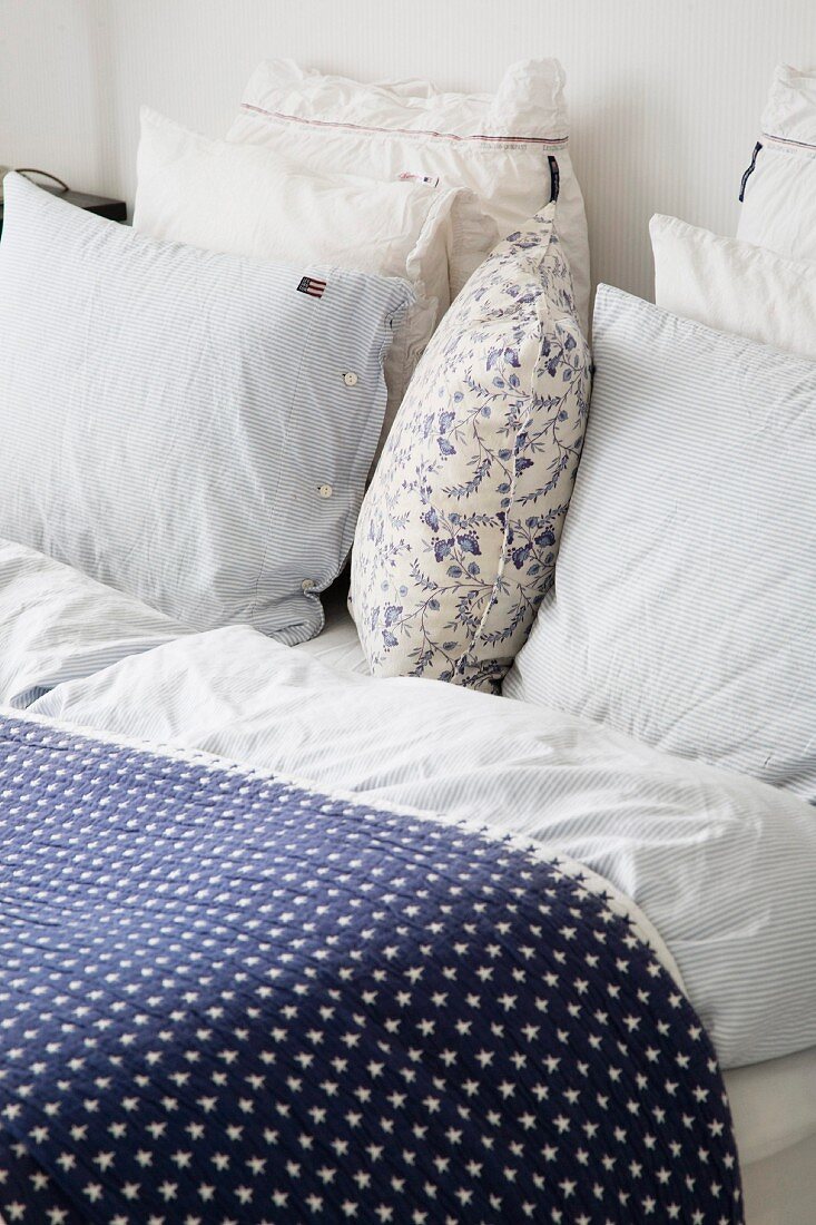 Bed cover with blue and white star pattern and stacked pillow on bed