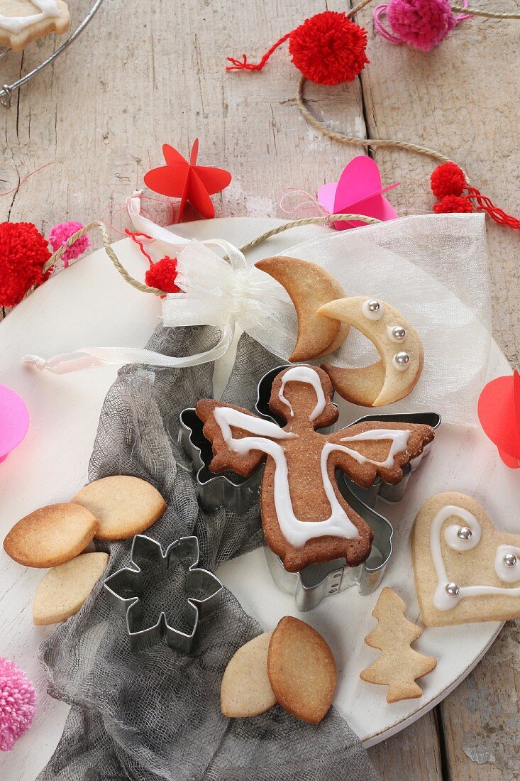 Decorated Christmas biscuits on a plate surrounded by Christmas decorations