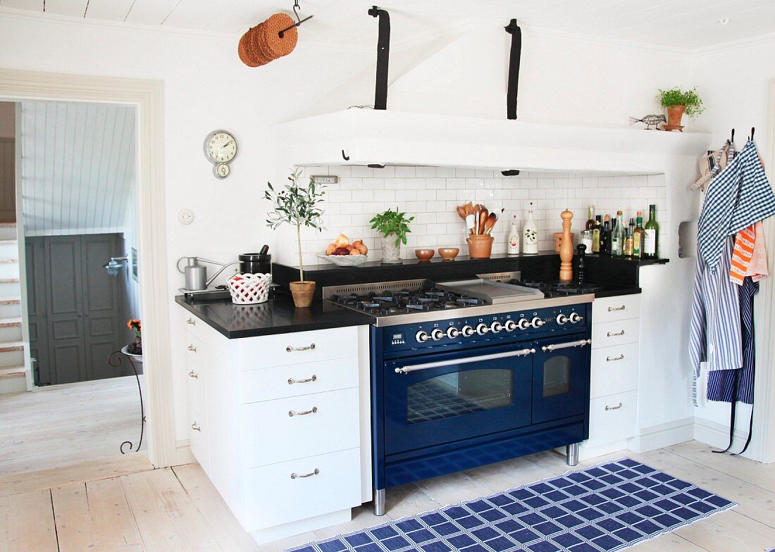 Blue rug in front of kitchen counter with blue, retro cooker and integrated extractor hood