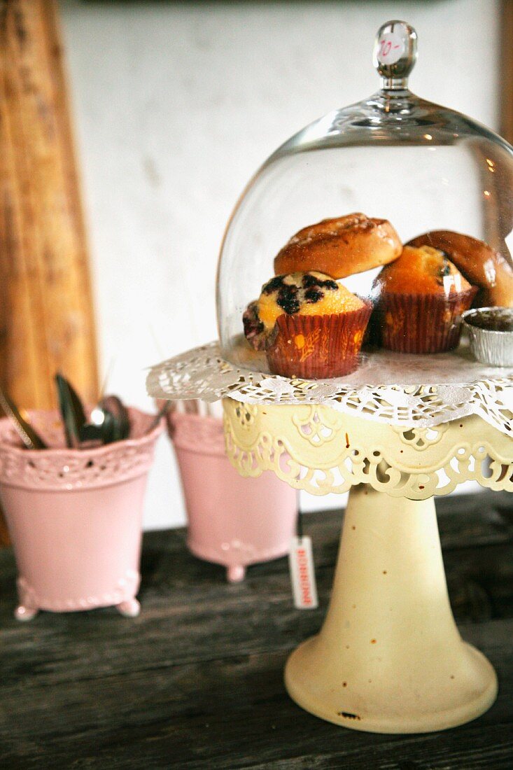 Muffins under glass cover on vintage, pastel yellow cake stand