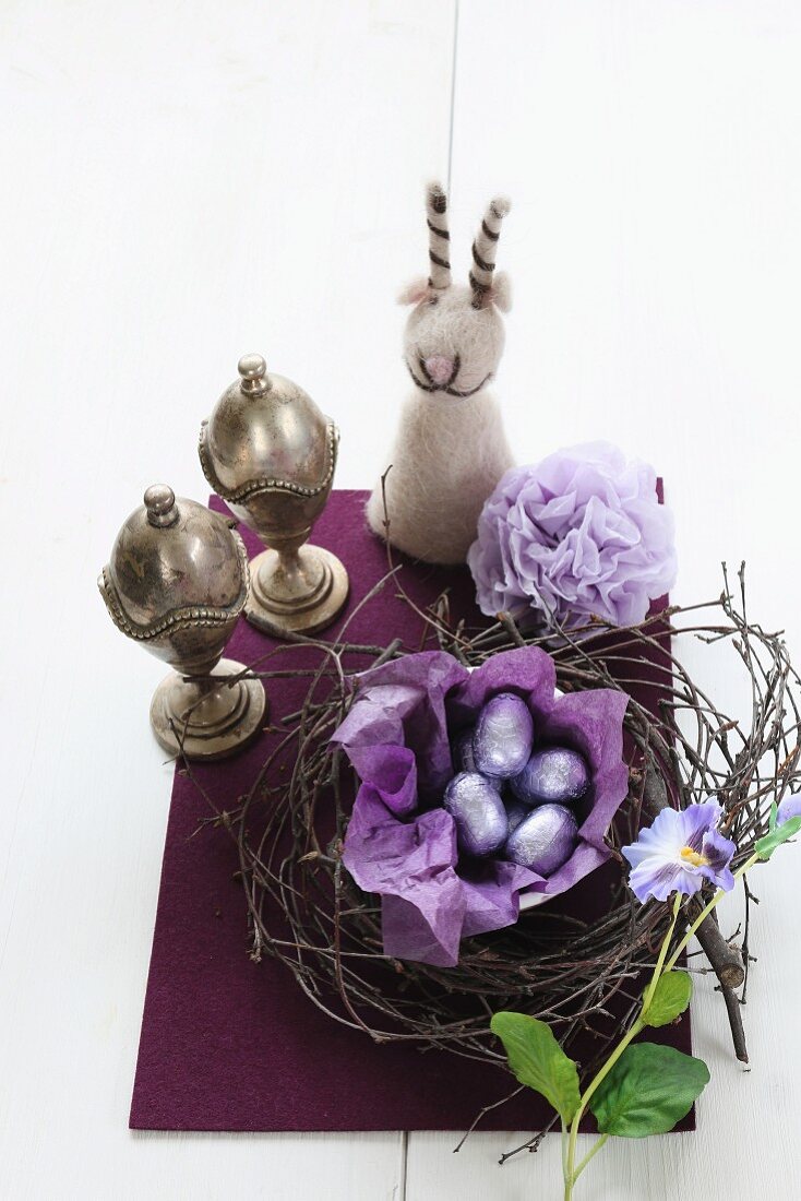 Chocolate eggs in Easter nest, two silver eggcups and felt egg cosy