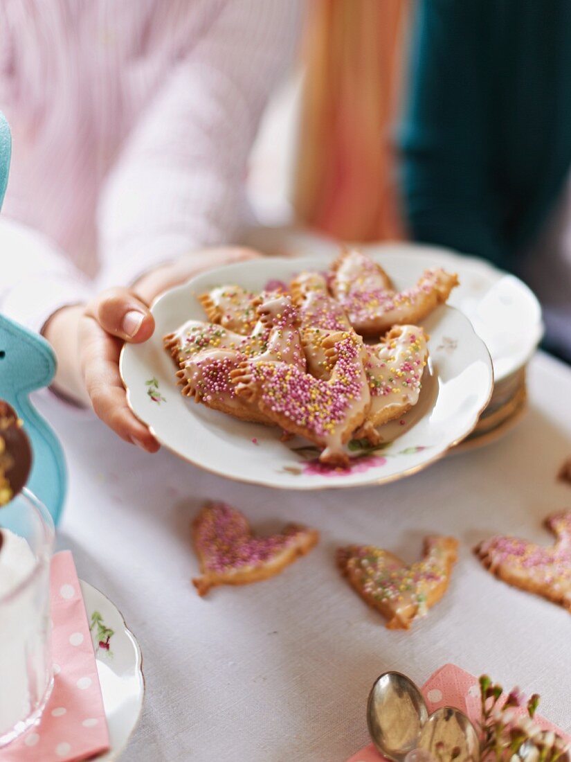 Hände halten Teller mit Osterplätzchen