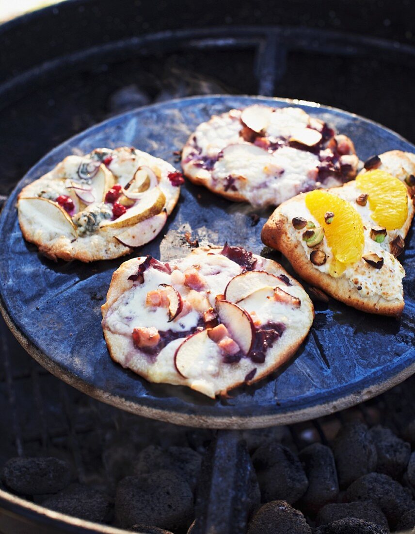 Various small pizzas on a barbecue
