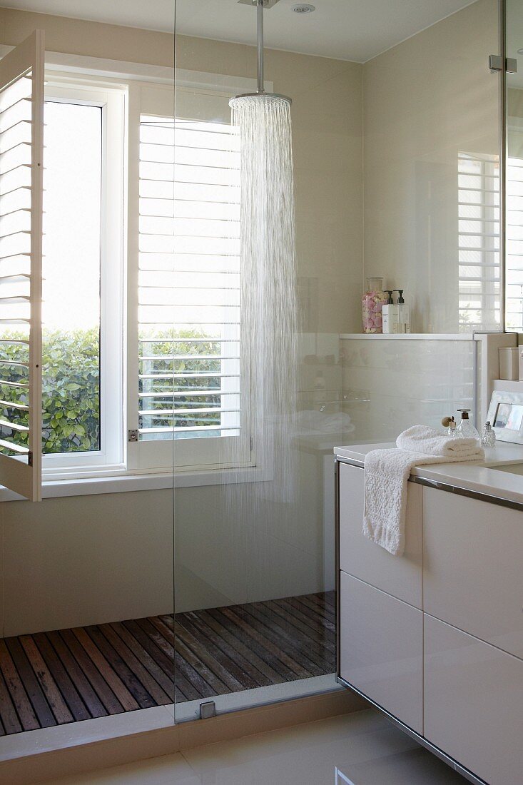 Detail of modern bathroom, partially visible washstand and glazed shower area next to window