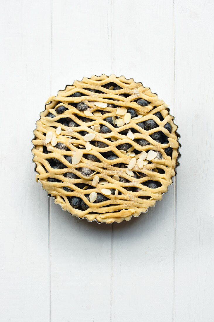 A whole blueberry pie with a lattice top in a baking tin