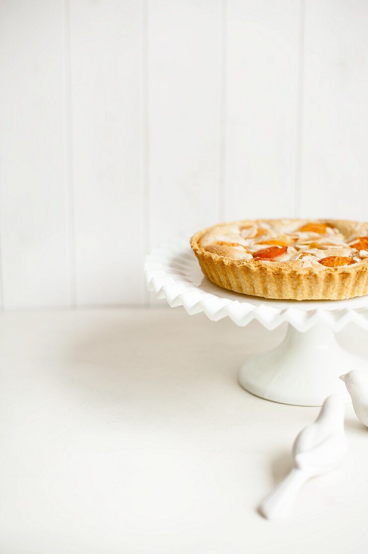 A whole apricots high with slivered almonds on a cake stand