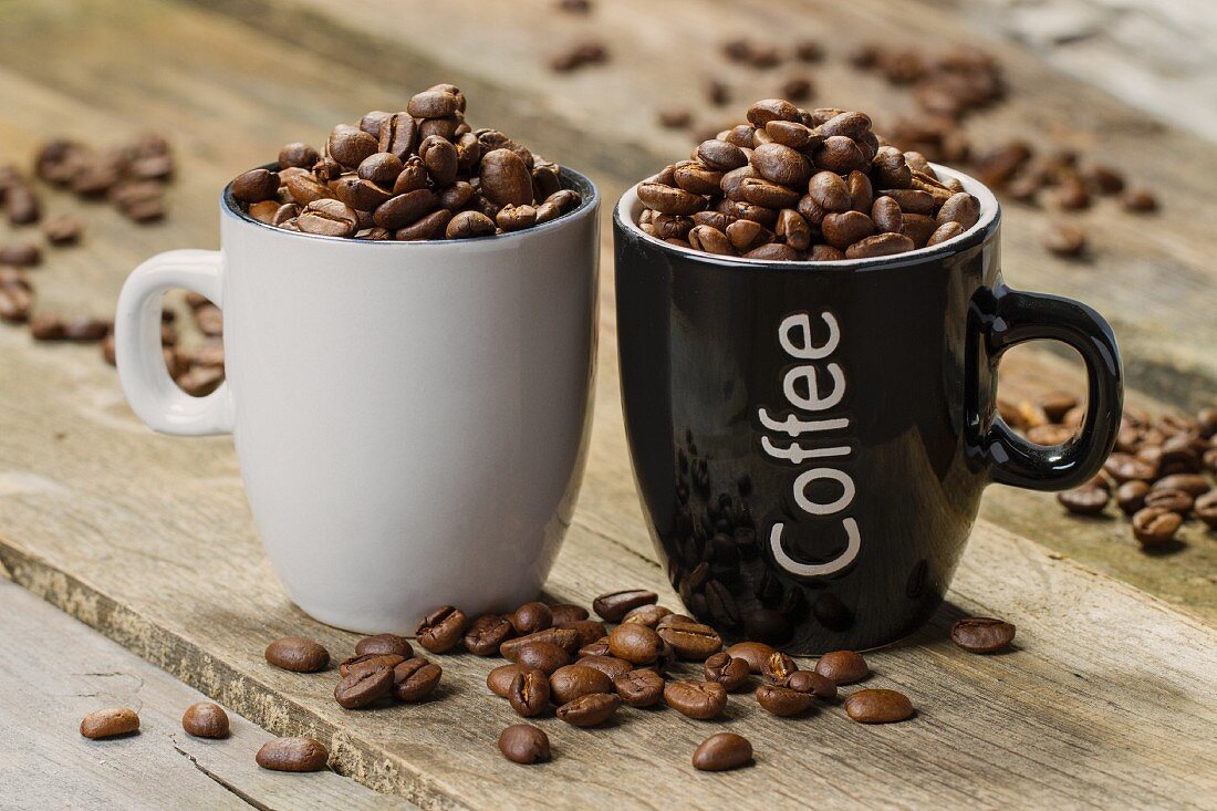 Two cups filled with coffee beans