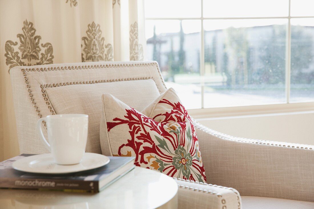 Detail of tea cup with book next to armchair; Irvine; California; USA