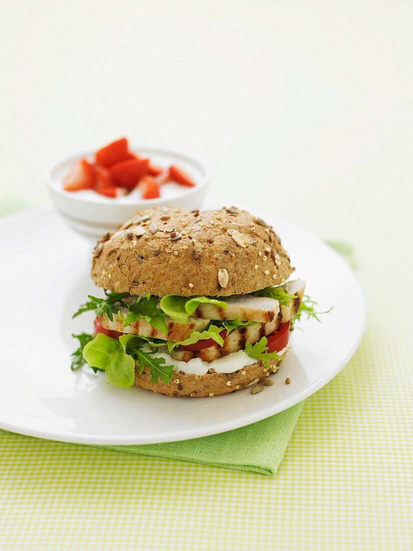 A grilled chicken burger on a wholemeal bun with lettuce and tomato