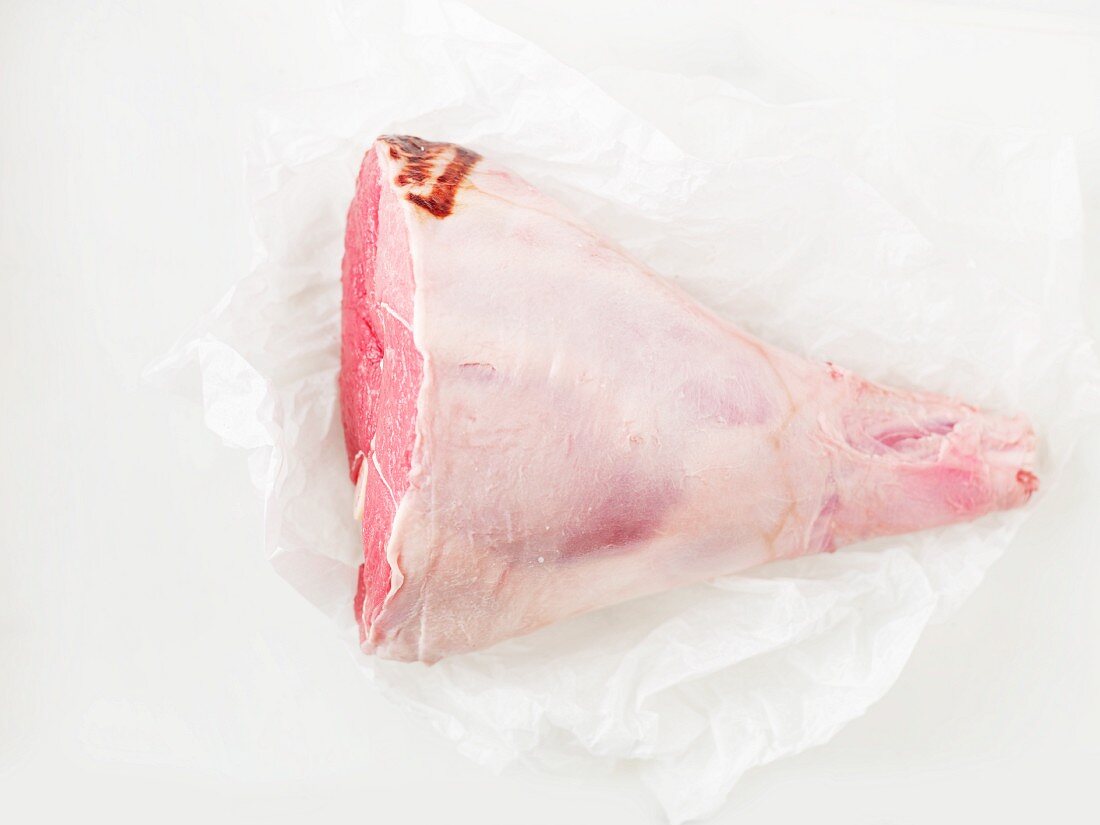Raw leg of lamb on a piece of parchment paper