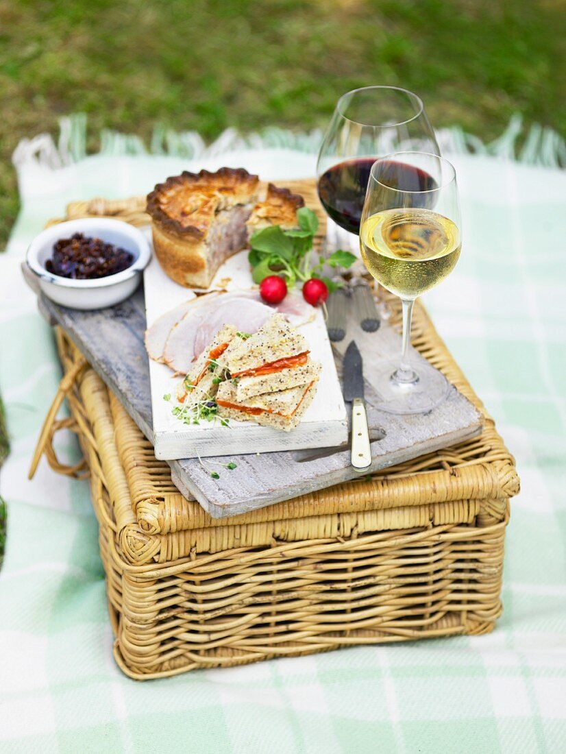 Tramezzini, a meat pie, ham and wine on top picnic basket