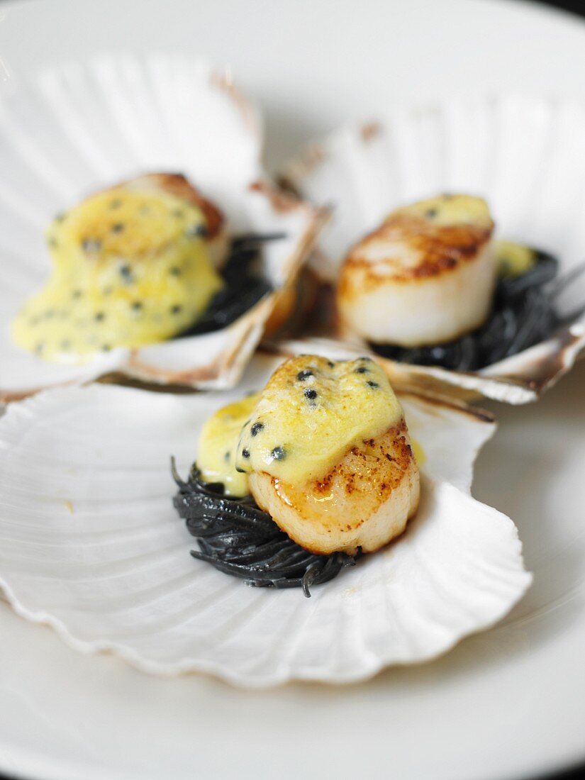Scallops on black spaghetti topped with melted cheese