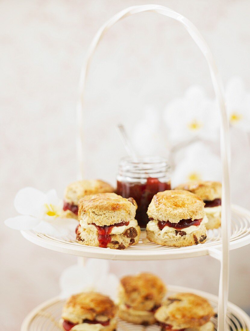 Scones with cream and strawberry jam on a white metal cake stand