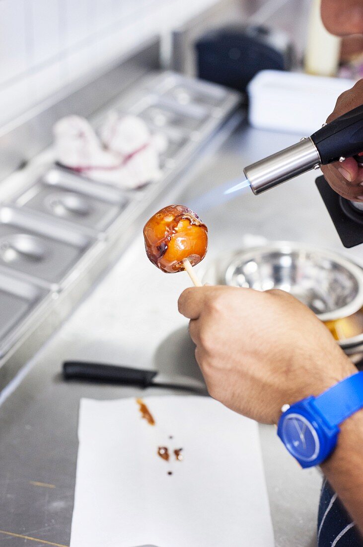 An apple being caramelised with a blow torch