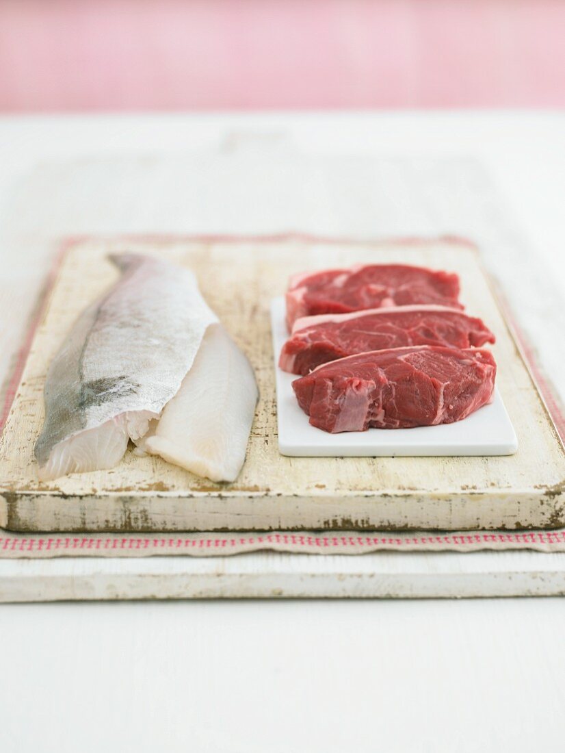 Fish fillets and lamb fillets on a chopping board