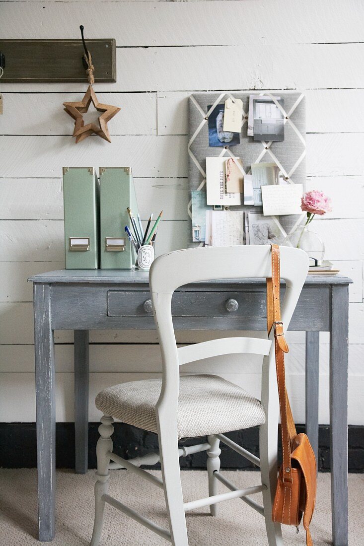Shabby Schreibtischplatz in Grau mit gepolsterter Pinntafel vor lackierter Bretterwand