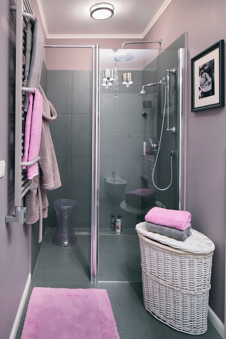 An open shower in an elegant bathroom with grey tiles, lilac-grey walls and lilac coloured towels
