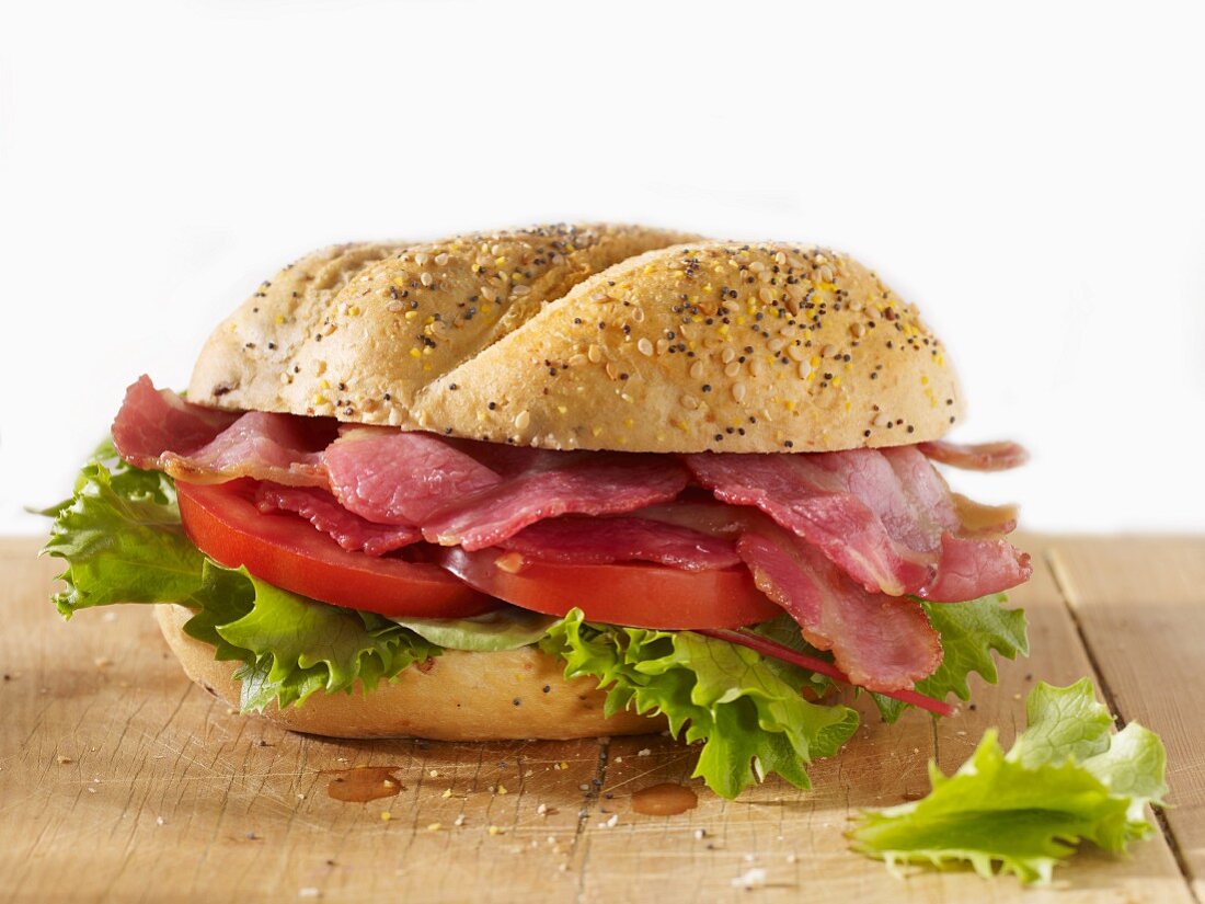 Bacon, lettuce and tomato poppy seed roll - BLT - on a wooden board