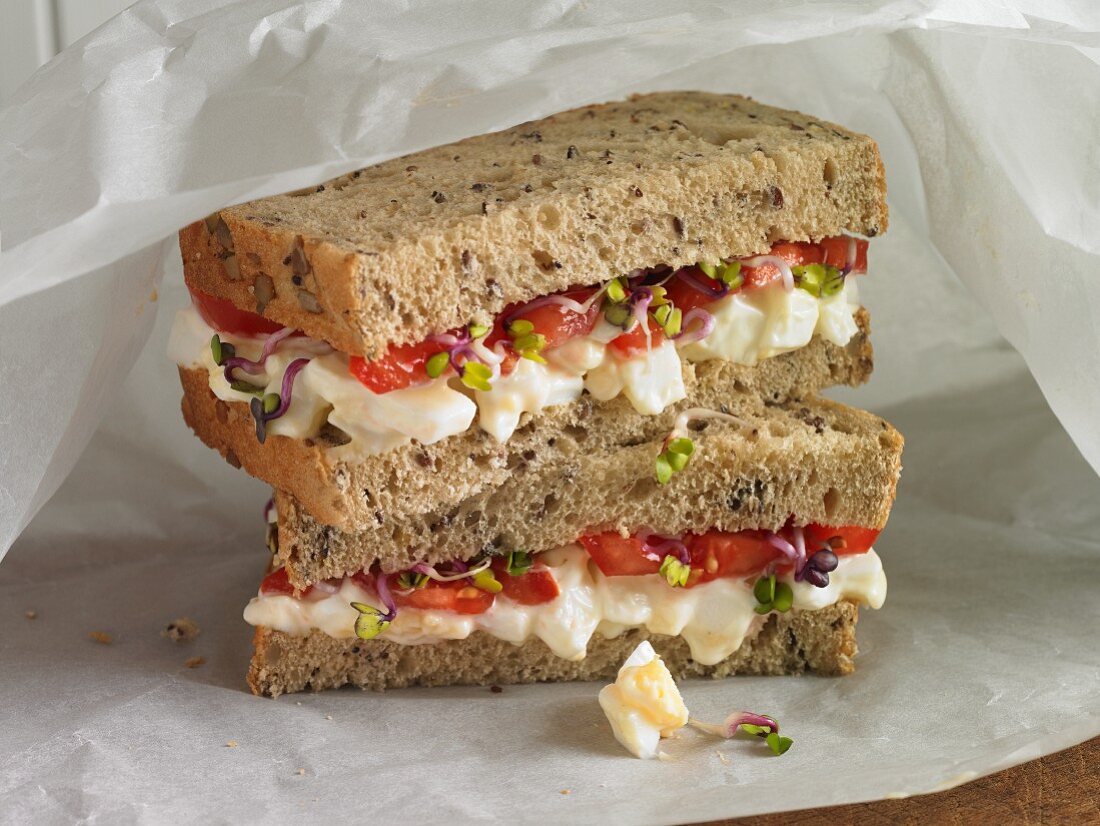 Bauernbrot-Sandwich mit Ei, Tomate und Kresse in Butterbrotpapier