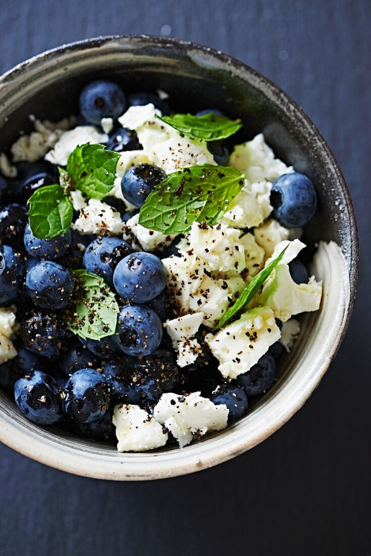 Blueberries with goat's cheese, mint leaves, pepper and olive oil