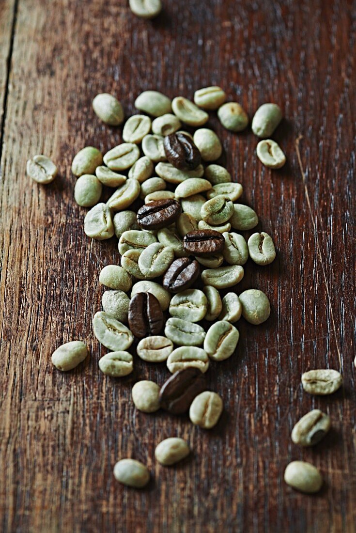 Green and roasted organic coffee beans on wooden surface