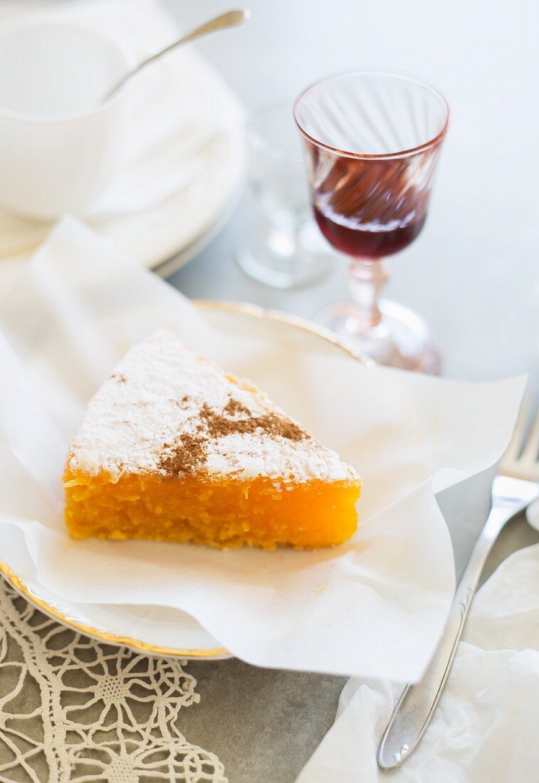 A slice of Toucinho do céu (almond and lemon cake, Portugal) with a glass of port wine