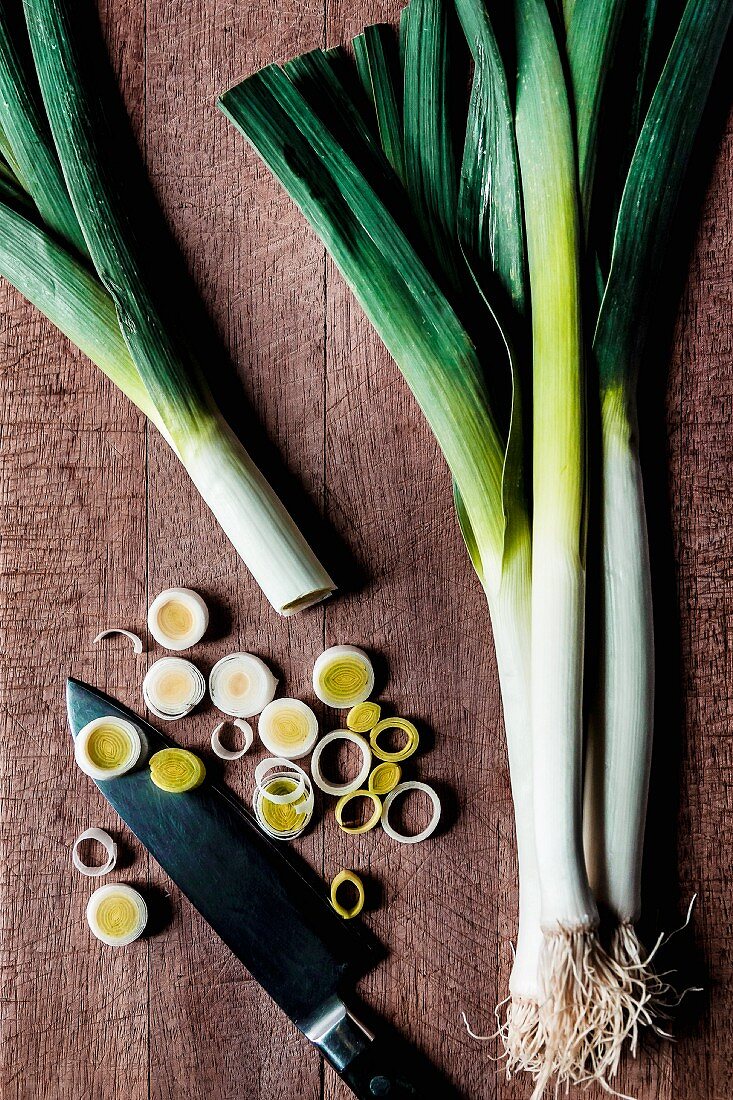 Leeks, whole and slices, on a wooden surface