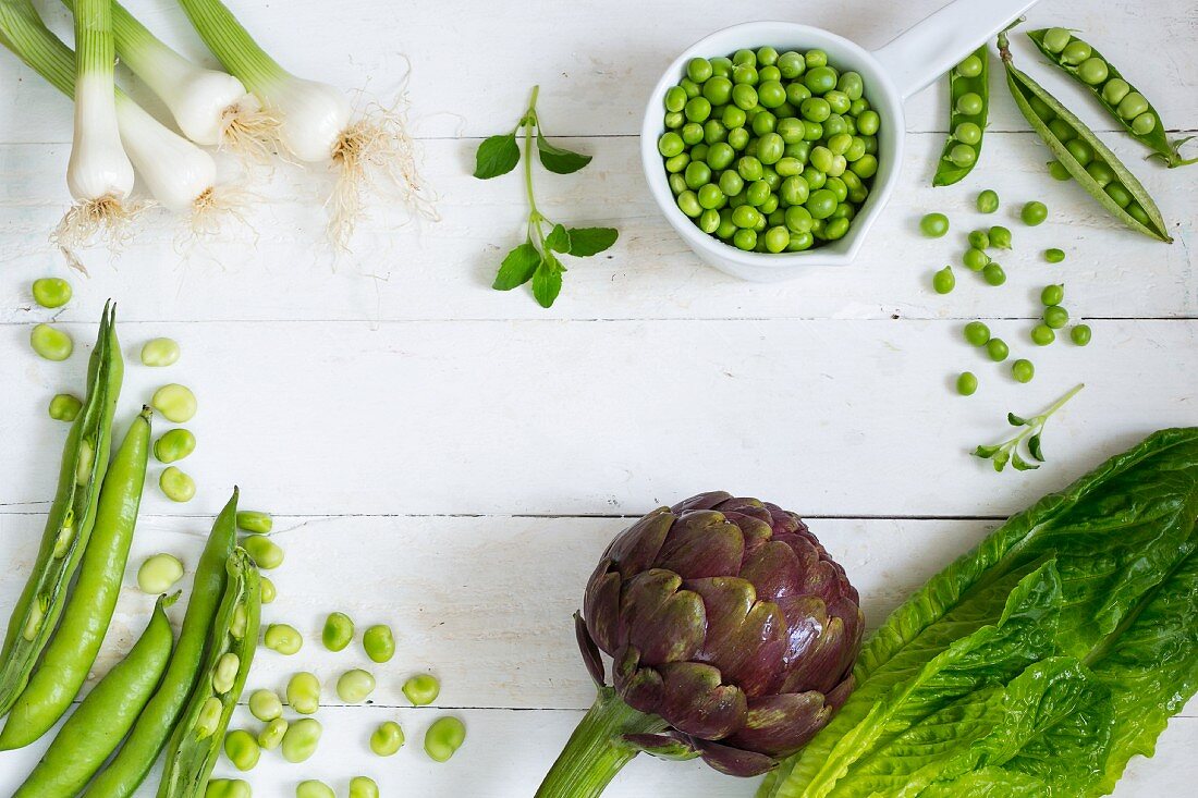 An arrangement of vegetables featuring a large artichoke and peas