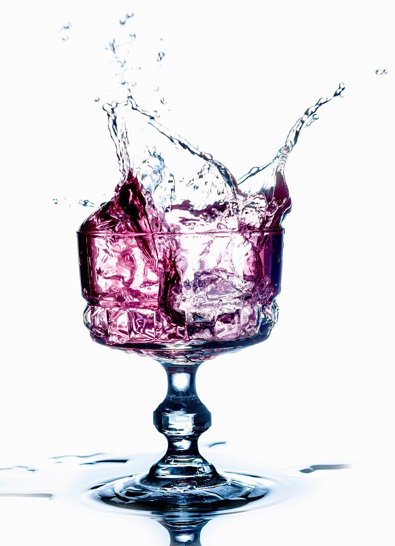 A purple drink splashing from a glass