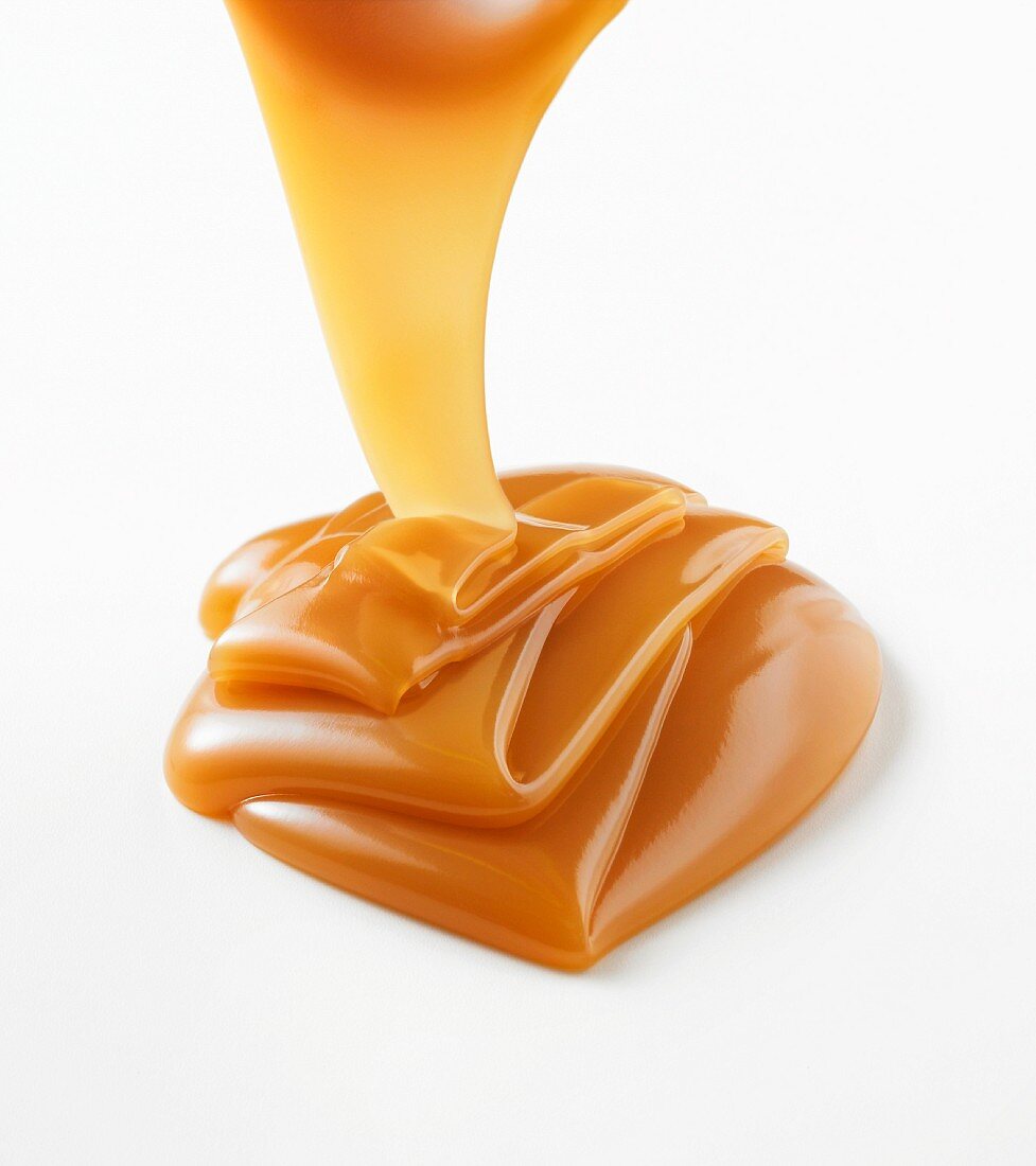 Caramel sauce being poured onto a white surface