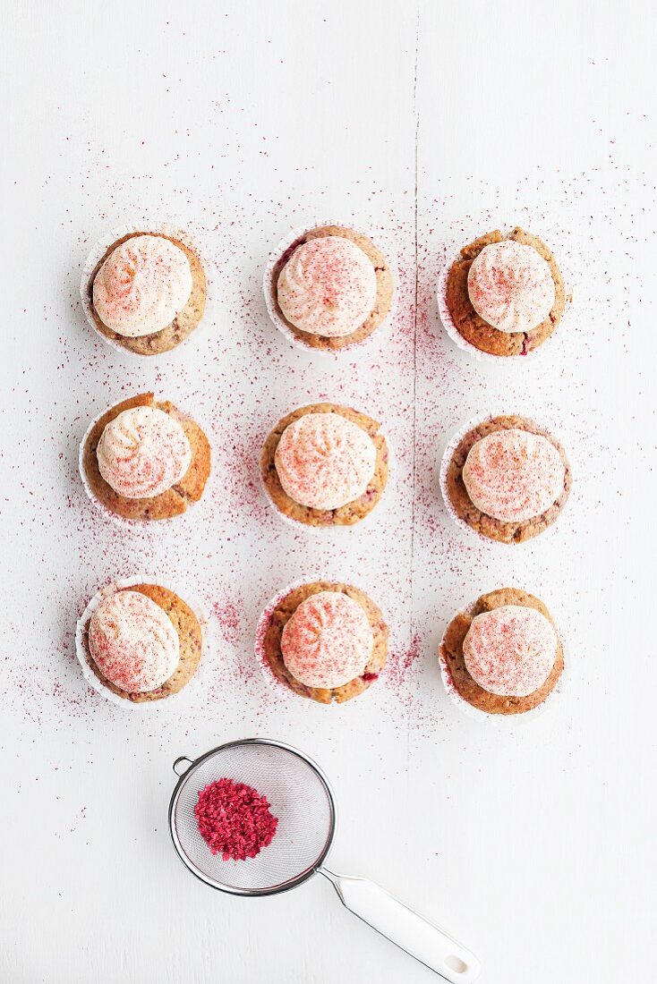 Raspberry and almond muffins decorated with buttercream and dried raspberry powder