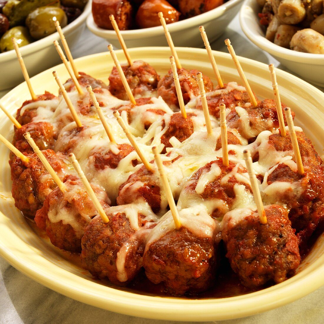 Meat balls in a spicy tomato sauce topped with melted cheese (Spain)