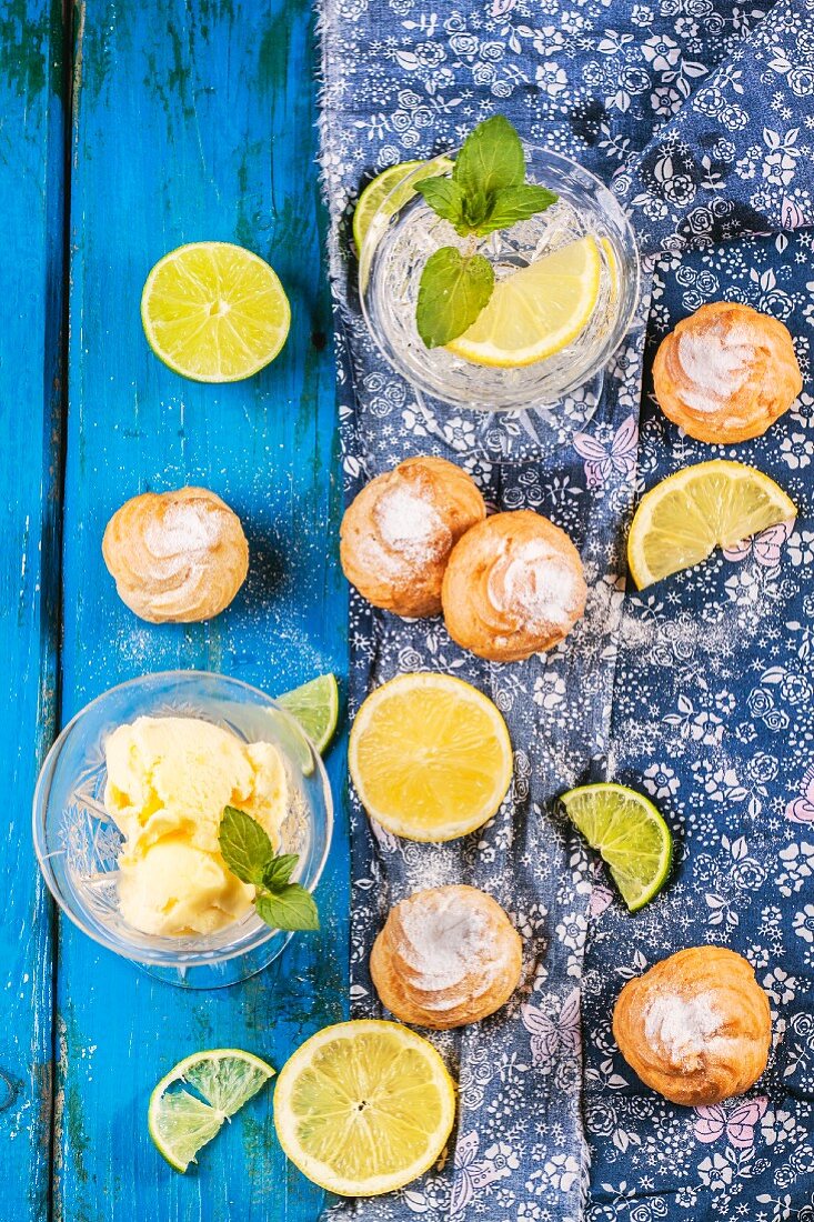 Hausgemachte Profiteroles mit Limonade und Eis auf blauem Holztisch