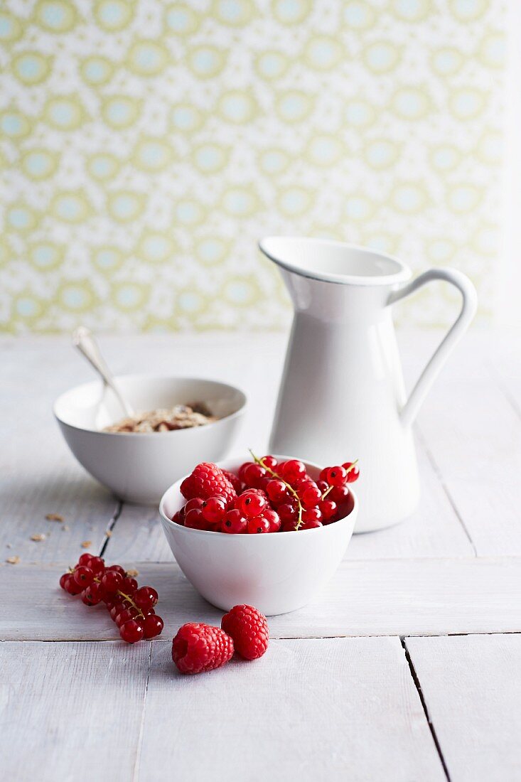 Raspberries, redcurrants, muesli and a jug of milk