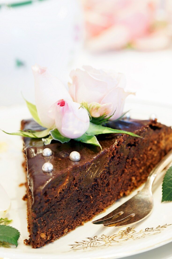 A sliced of chocolate cake decorated with roses
