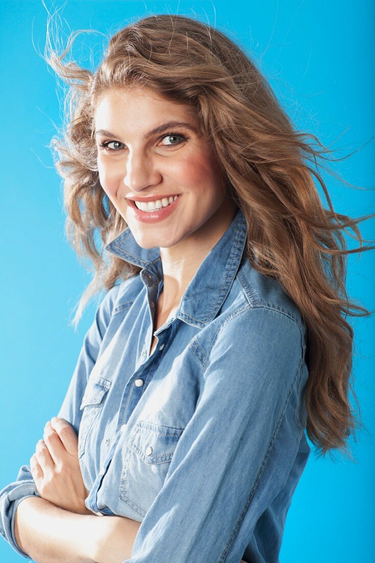 A young brunette woman with her arms folded wearing a denim shirt