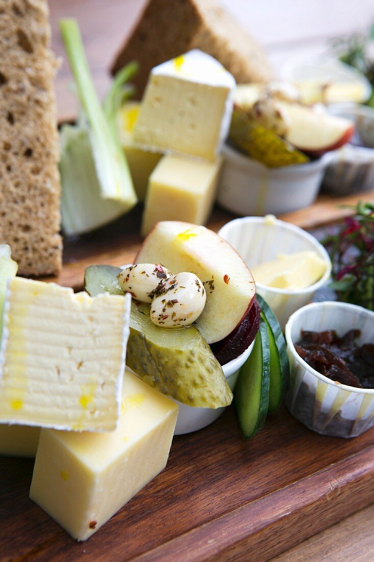 A cheese platter featuring pickled vegetables, fruit and bread